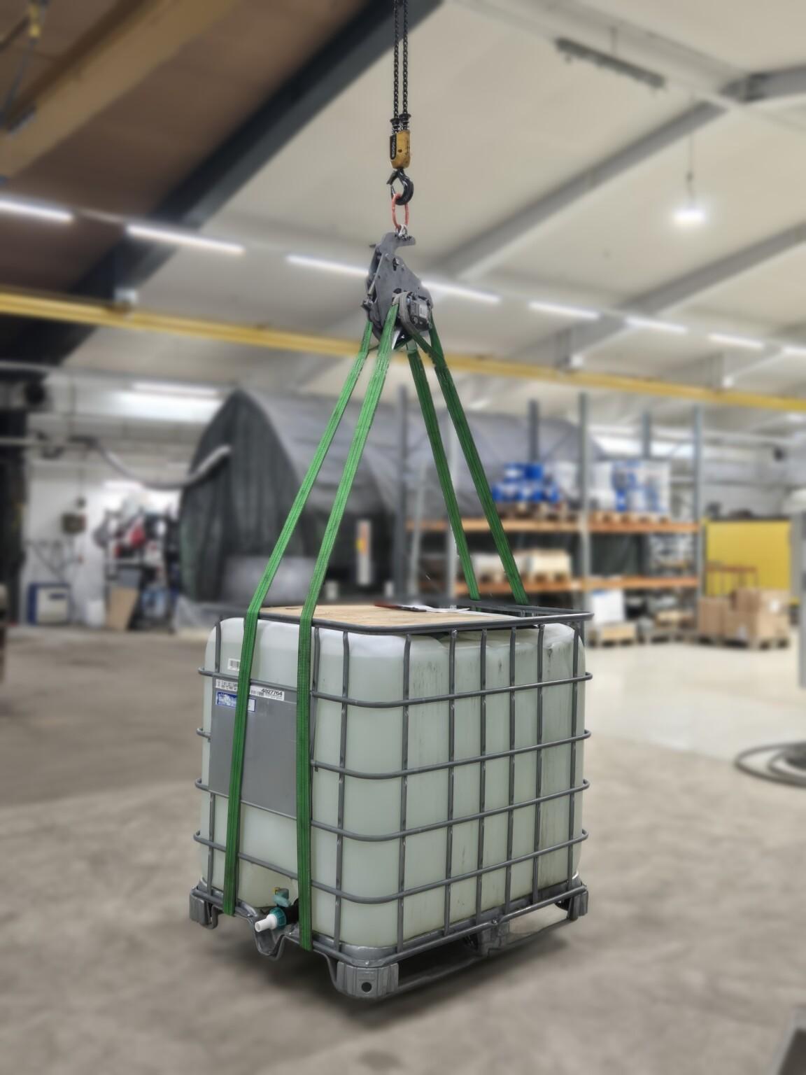 Prüfbelastung eines Lastaufnahmemittels in der Werkstatt – ein mit Wasser gefüllter IBC-Behälter hängt als Prüflast an Hebebändern